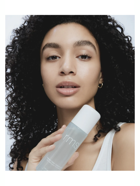 Woman holding Kakadu Clean Cleansing Gel by RMS Beauty with a plain background