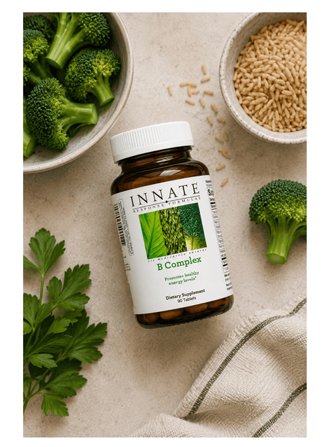 Innate B Complex supplement bottle with broccoli, rice, and parsley on a beige surface