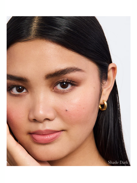 Close-up of a woman with dark hair and earrings, with 'Shade Dark' text at the bottom. Back2Brow Pencil by RMS Beauty