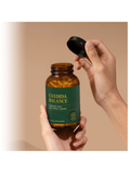 Hand holding a bottle labeled 'Candida Balance' against a beige background
