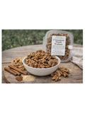 Cinnamon maple walnuts in a bowl and packaging on a wooden surface with a natural background.
