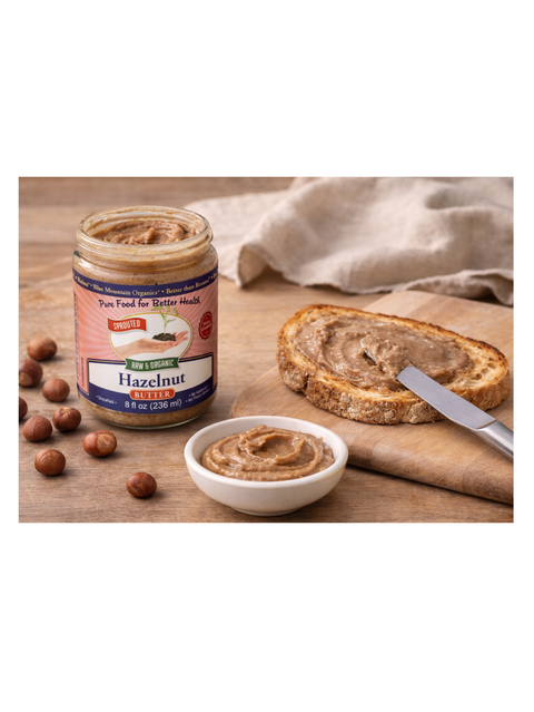 Jar of Hazelnut Butter, Sprouted, 8oz, Blue Mountain Organics on a wooden table with bread and nuts.