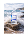 Bottle of Bioccean product on a rocky beach with ocean waves.