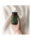 Hand holding a bottle of Global Healing Iron supplement against a white background