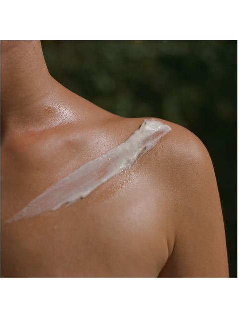 Close-up of a person's shoulder with a white cream or lotion applied.