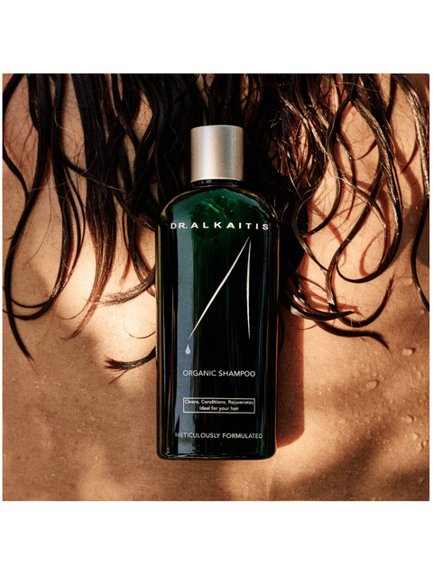 Dr. Alkaitis organic shampoo bottle with hair in the background