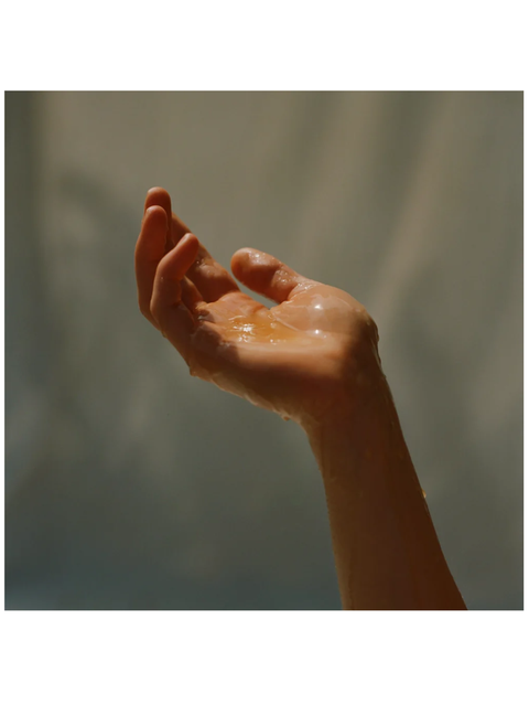 Hand holding a small amount of liquid against a blurred background