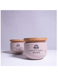 Two pale pink body scrub jars with light wood lids on a white surface against a light gray background. The front jar reads 'PACHA SOAP CO.