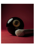 A glossy black 8-ball pool cue resting on a red surface against a dark red background with a skin2skin foundation brush by RMS Beauty.