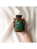 Hand holding a bottle of 'Ultimate Enzymes' supplement against a white background